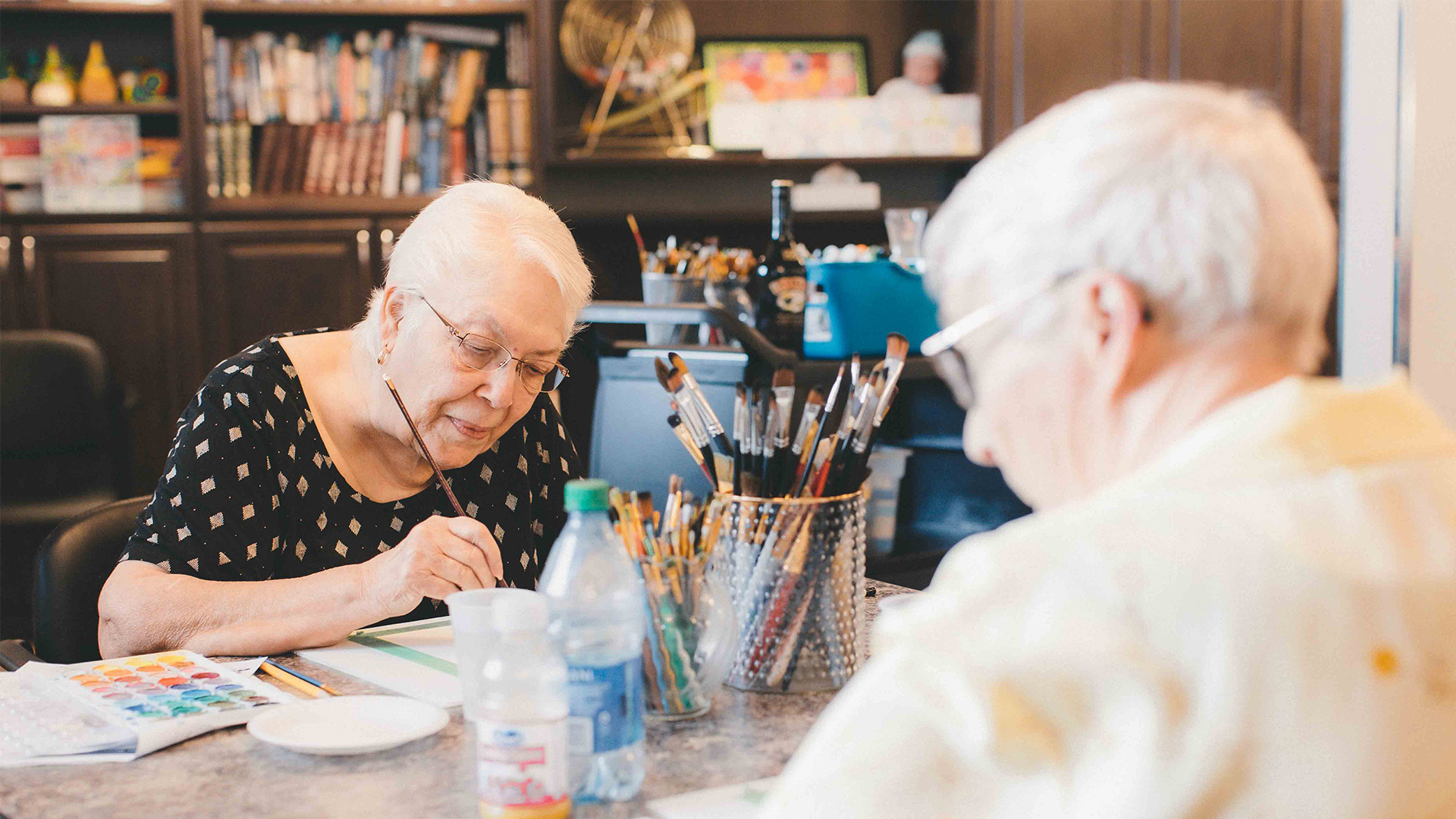 Header image featuring two seniors painting together