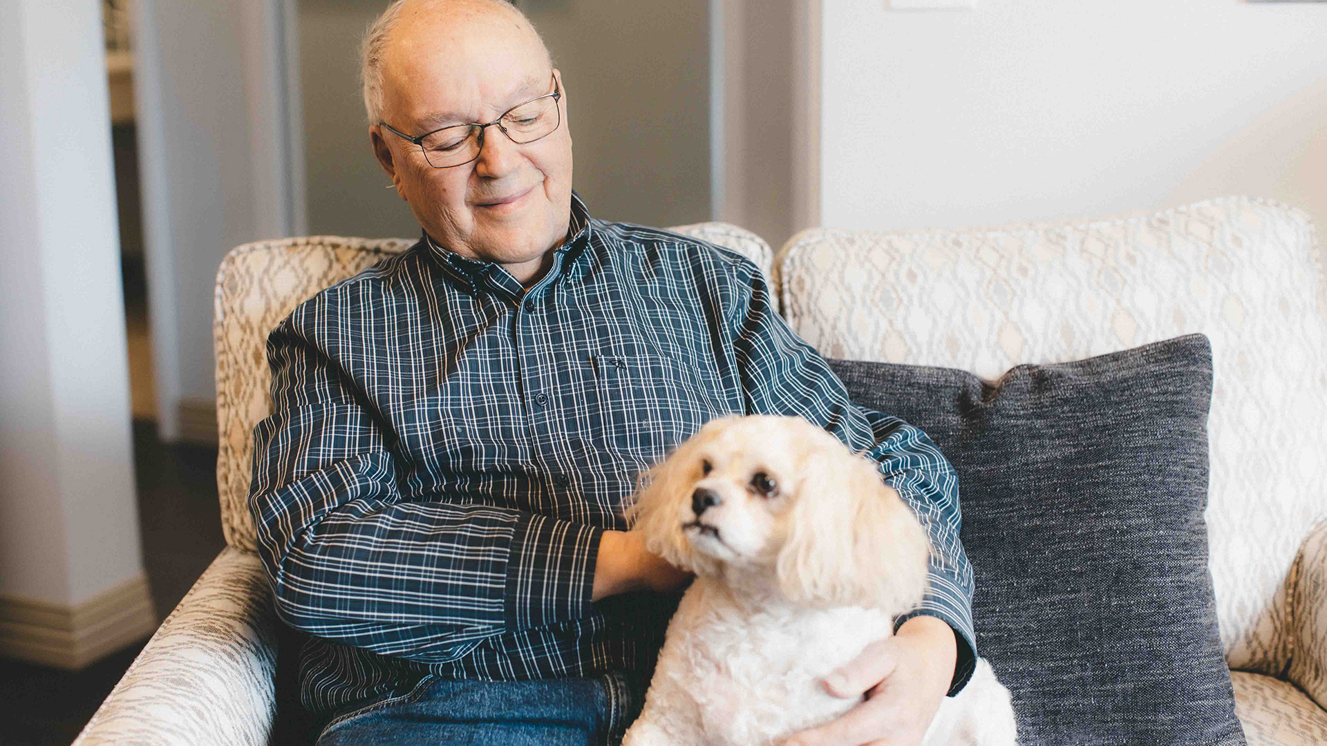 Header image of a senior smiling while holding his dog.