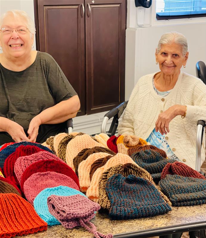 Two seniors with hats they sewed together for those in need