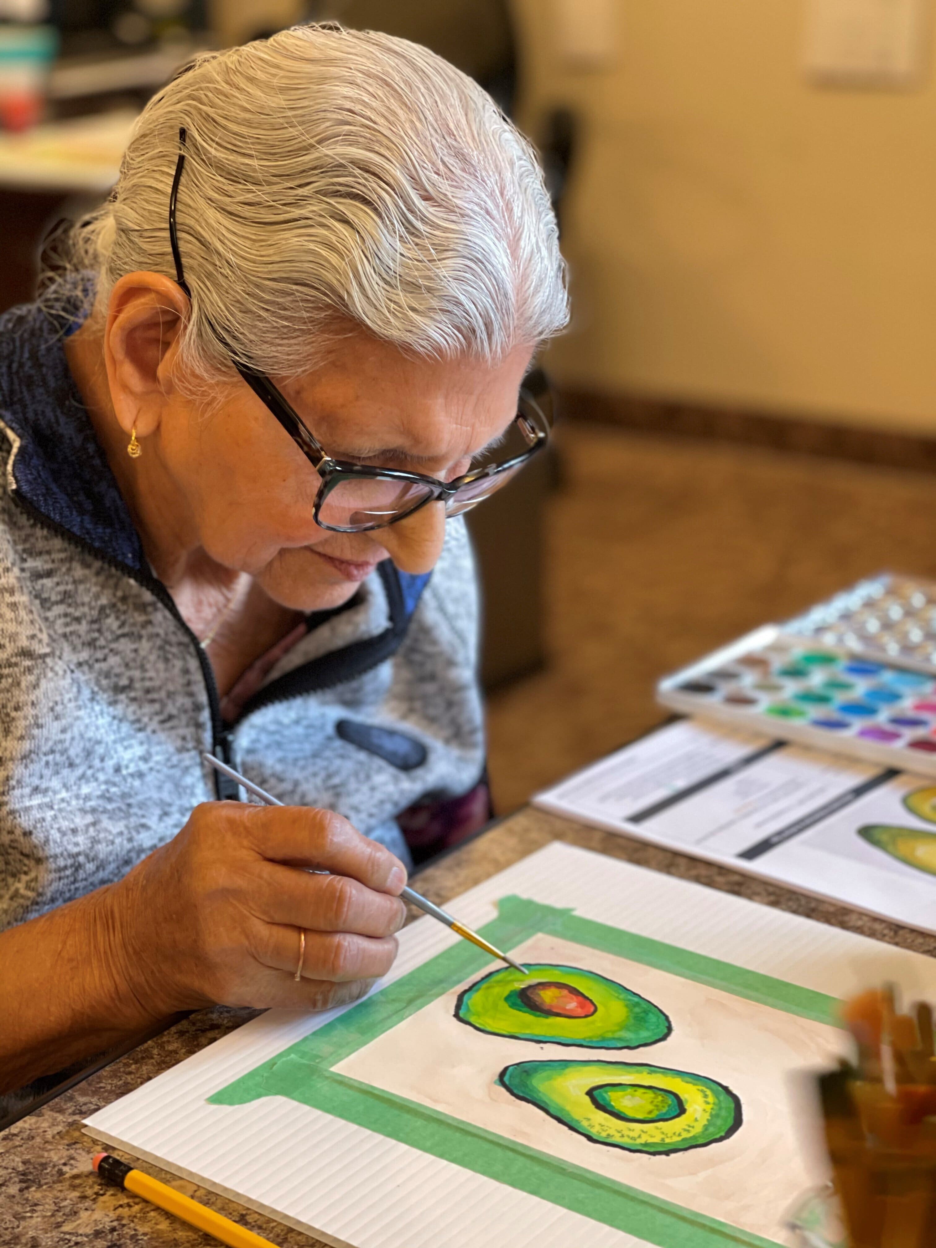 An elderly lady painting avacado in senior living