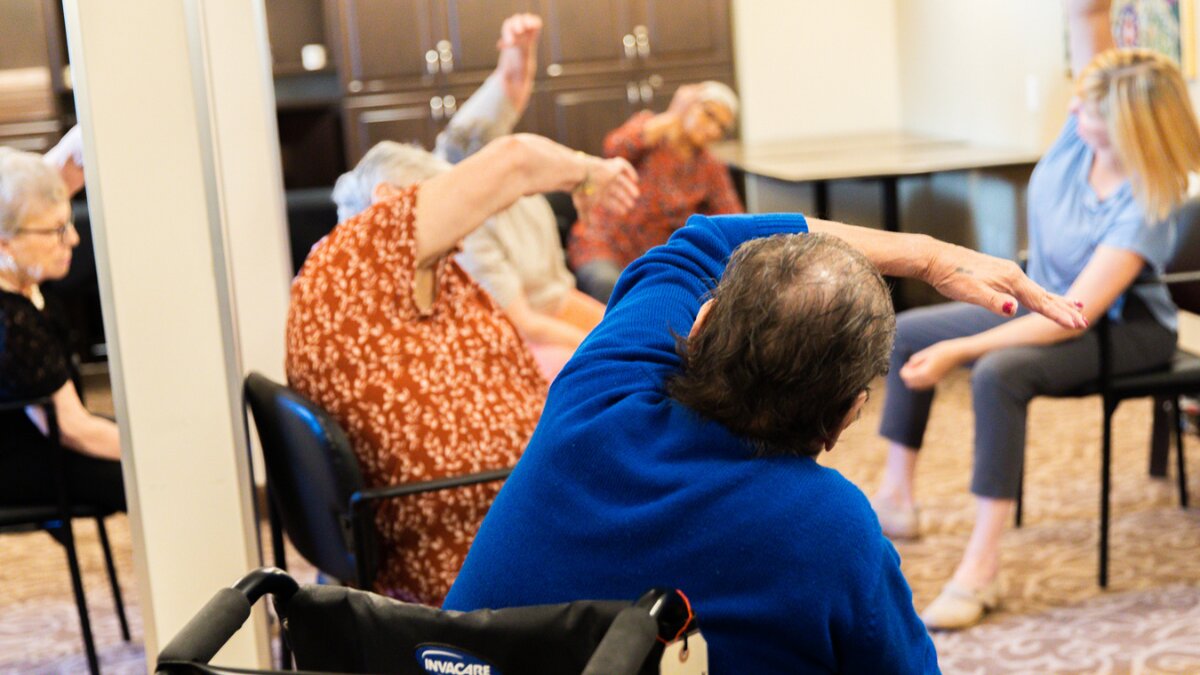 A group of elderly citizens doing chair exercises for seniors