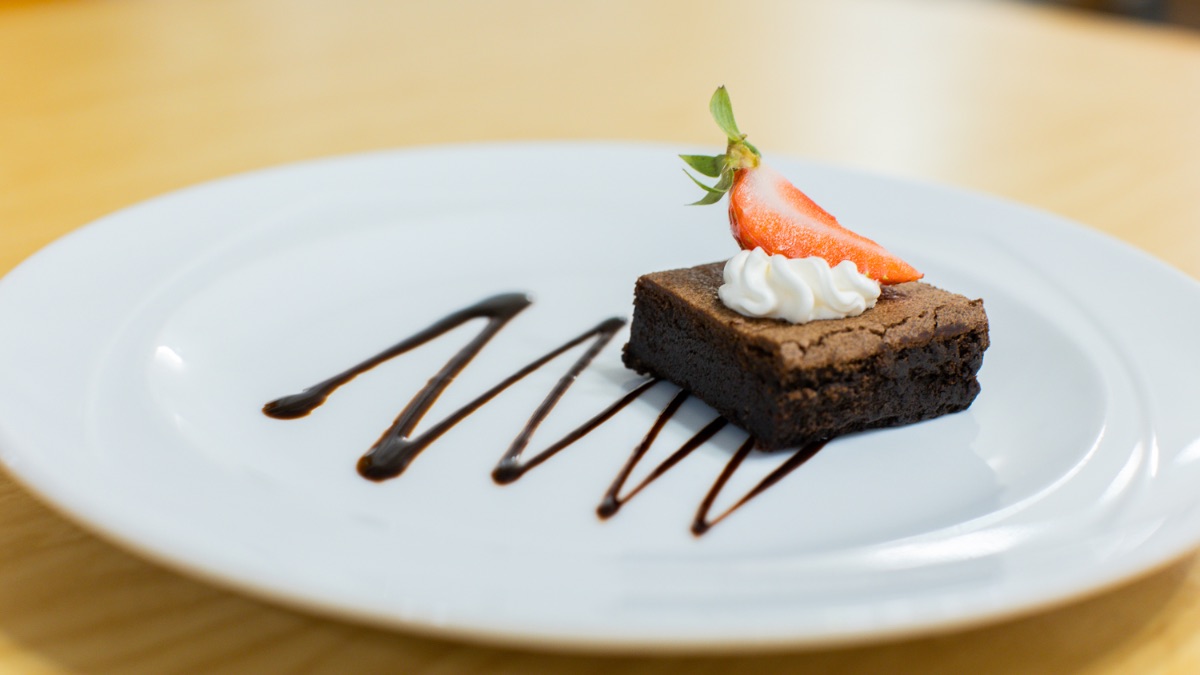 Chocolate brownie with a strawberry and whipping cream, a soft snack for elderly