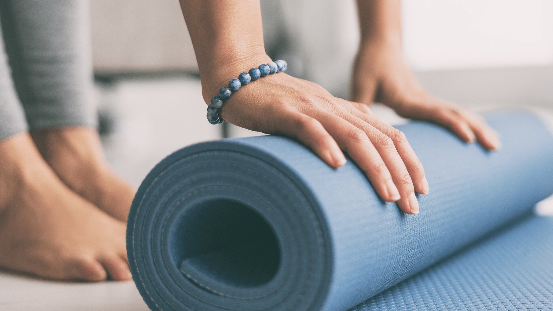 A lady rolls up a yoga mat, exercise programs for seniors