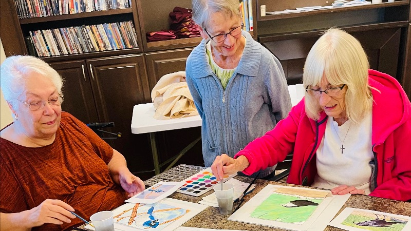 A group of seniors painting in a senior living community