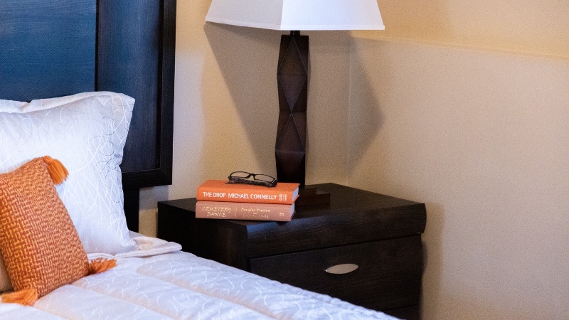 A picture of a lamp on side table with two books on it in senior apartments
