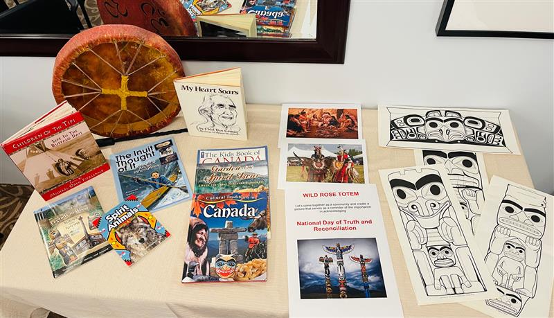 Table displaying some books, colouring sheets, and a drum for Truth and Reconciliation day in a senior living community