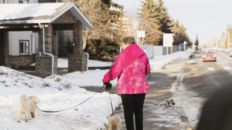 An elderly lady walking her two dogs outside senior living