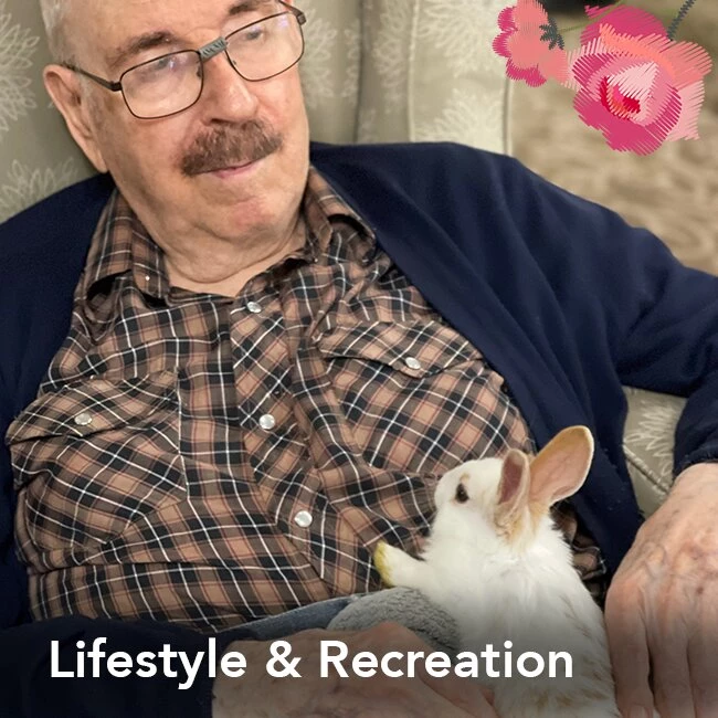 An elderly man playing with a rabbit in a senior home