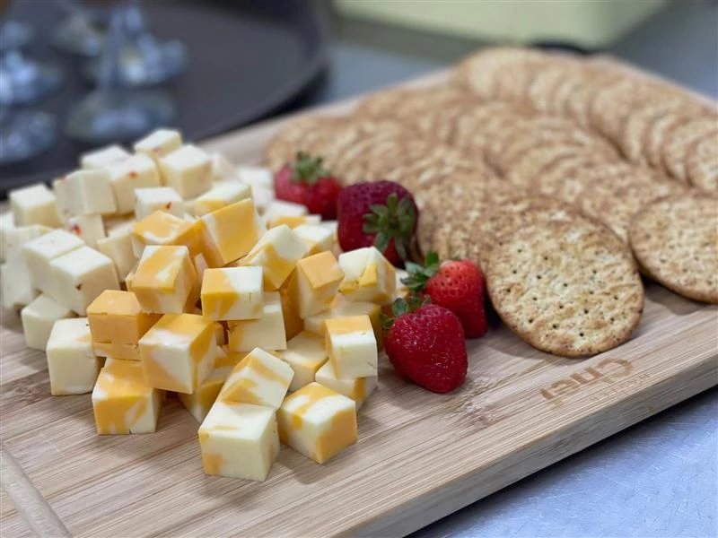 A charcuterie board with crackers, strawberries, and cheeses on it. Soft snacks for elderly.