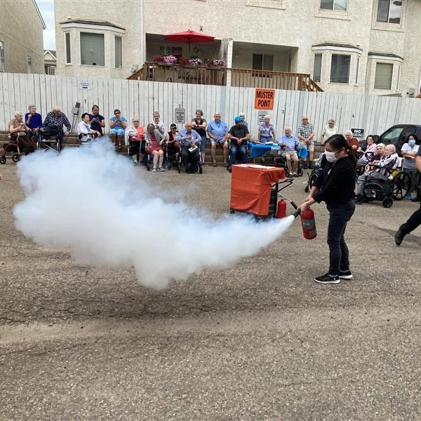 Woman displaying how to use a fire extinguisher for the residents of an elderly care home