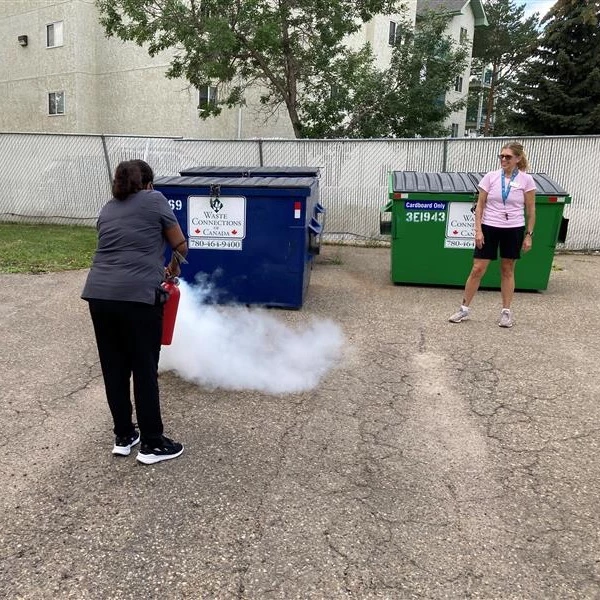 Two women practicing with a fire extinguisher outside a retirement home