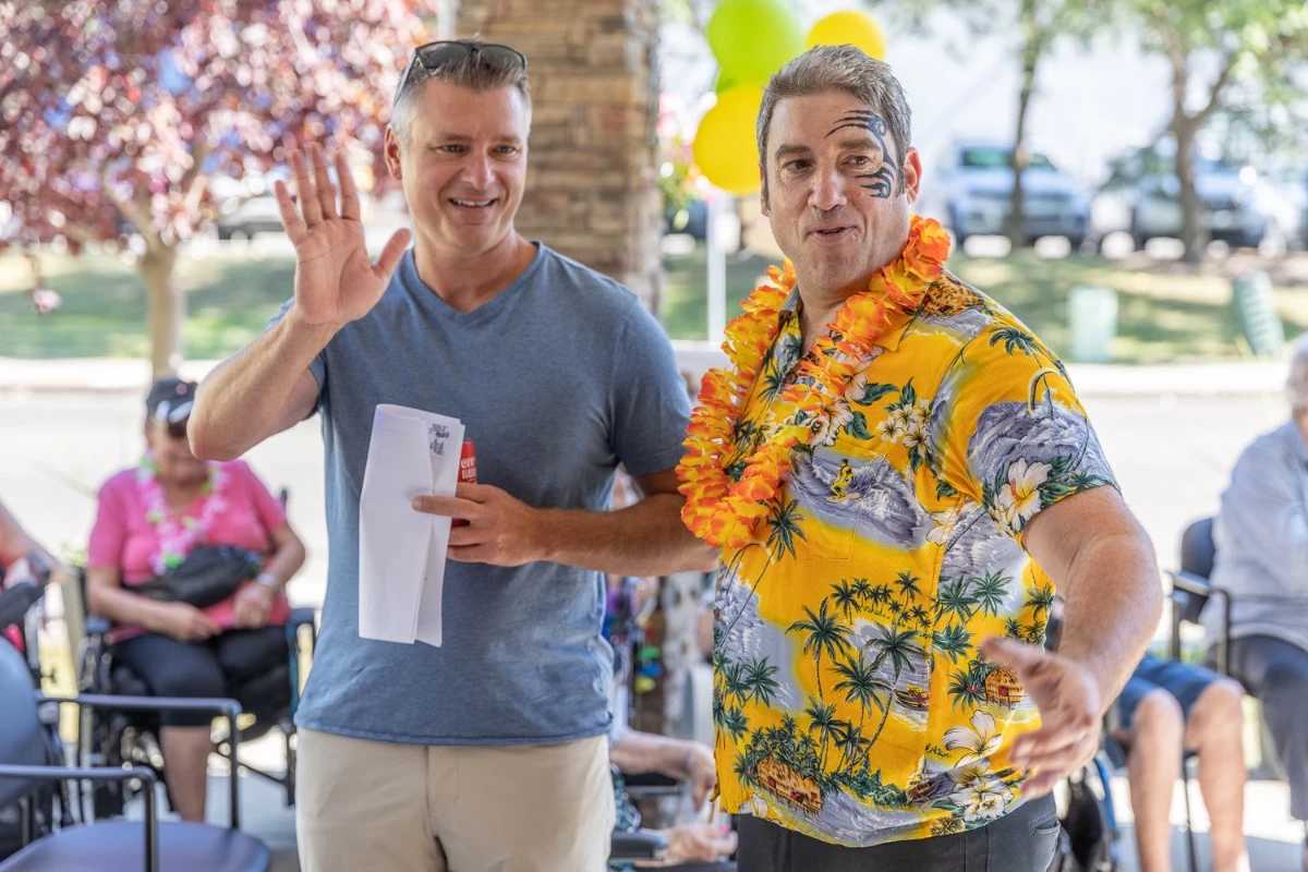 Louis Bloom in a Hawaiian outfit entertaining the residents of a senior living community outside.