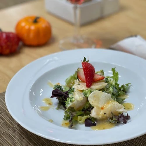 A nice looking salad garnished with a strawberry and dressing. Healthy meals for seniors.
