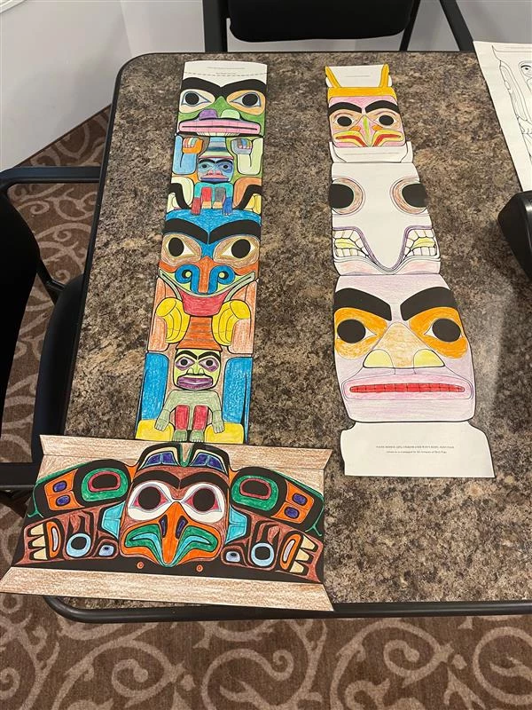 Totem pole colouring pages displayed on a table in a retirement home.