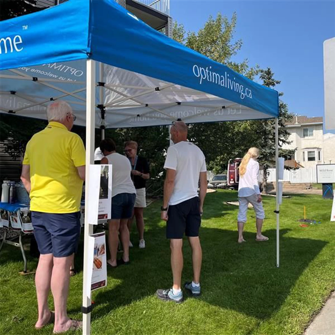Seniors standing under an Optima Living tent