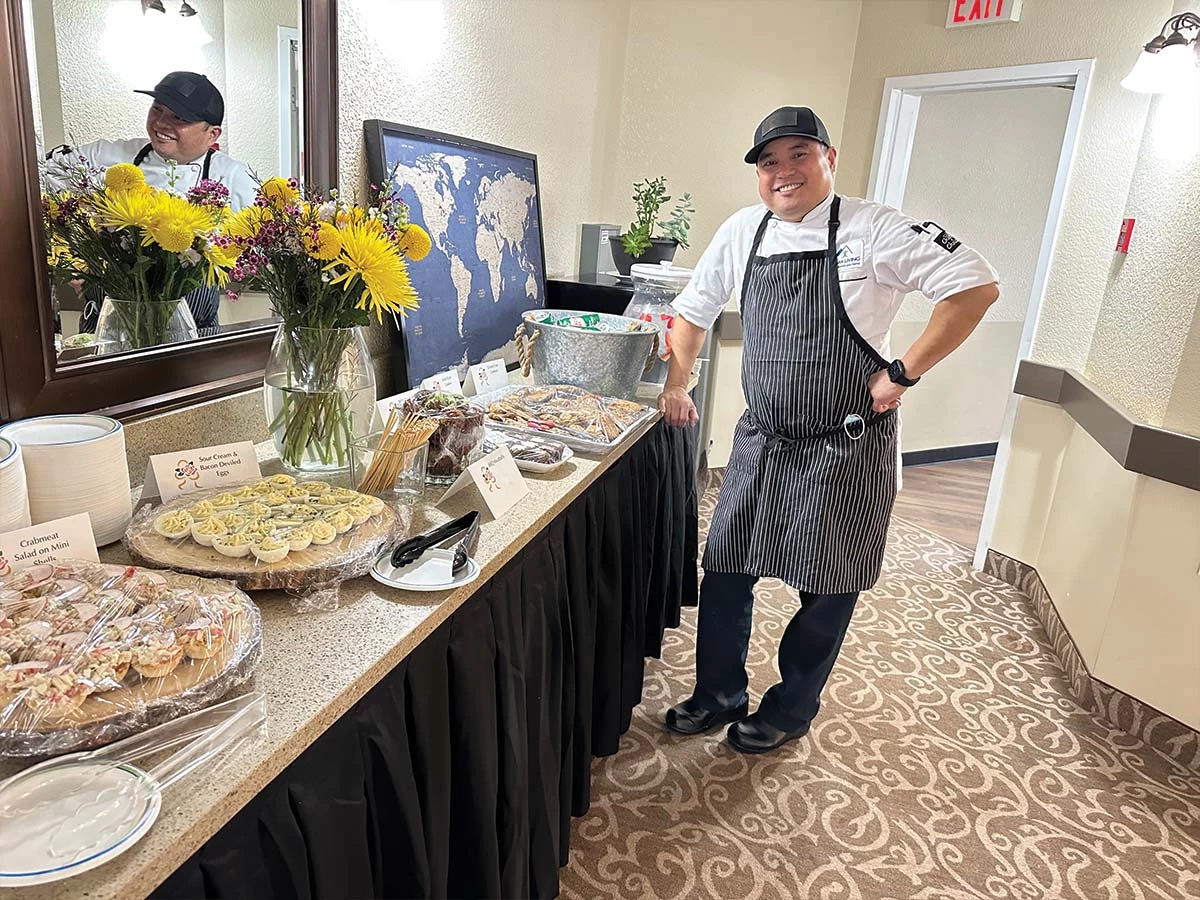 The Wild Rose chef standing next to some tables of food